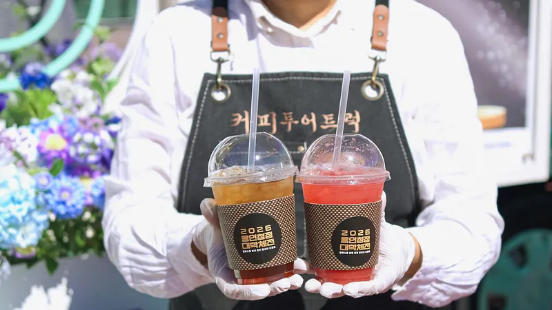 커피투어트럭 앞치마를 입은 바리스타가 음료 두 잔을 든 모습